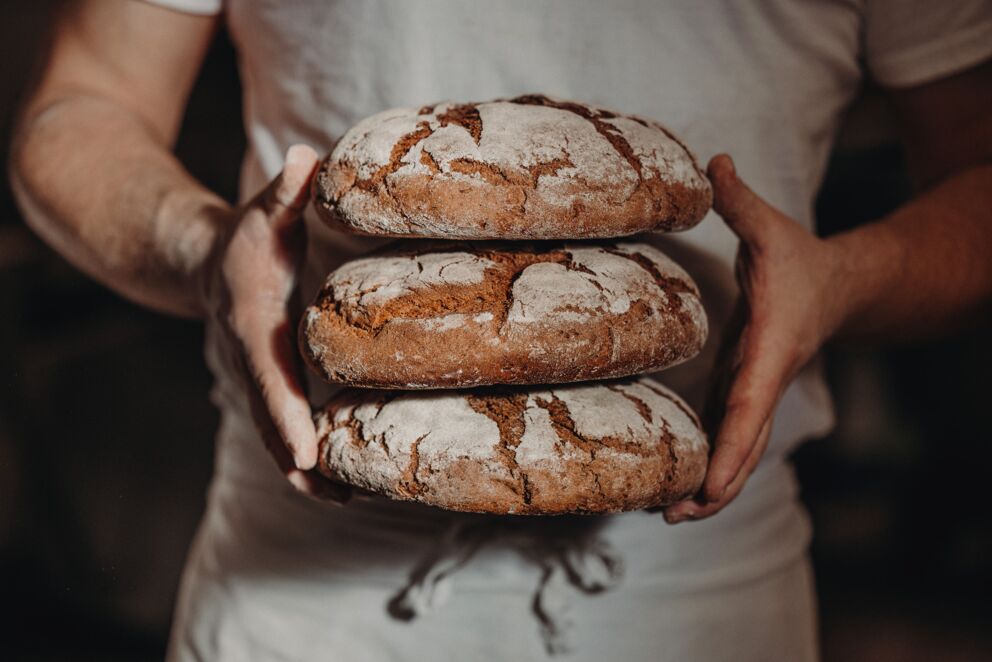 Bäcker mit frischen 3 Laib gebackenes Schwarzbrot