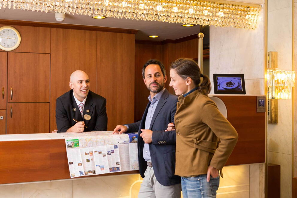 Eine Frau und ein Mann werden an der Rezeption von einem Hotel-Rezeptionisten beraten