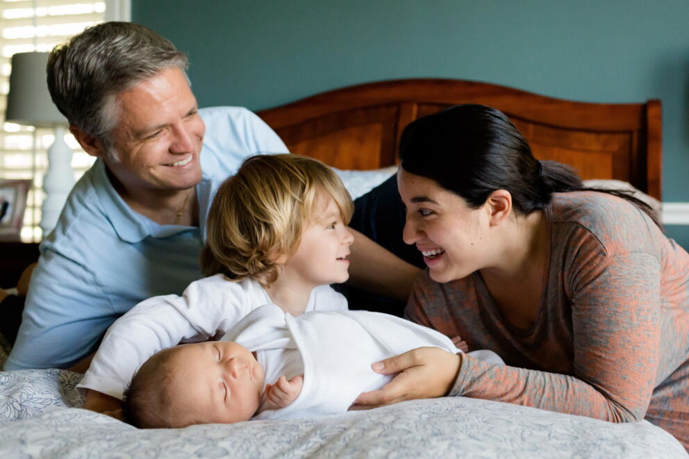 Glückliche Familie mit neugeborenem Baby zusammen in einem Bett