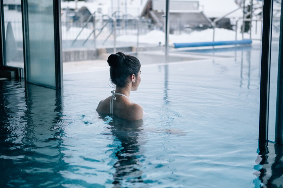 Eine Frau schwimmt im Außenbereich des Schwimmbades des Schlosshotels Fiss
