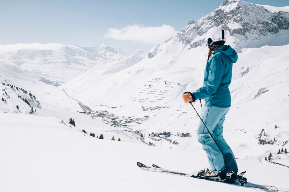 Eine Skifahrerin am Arlberg blickt hinunter auf den Ort Zürs © Daniel Zangerl - Lech Zürs Tourismus