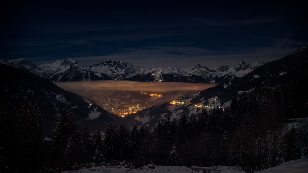 Winterliche Berglandschaft mit Blick auf das beleuchtete Tal
