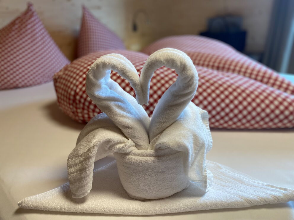 Liebevolle zu einem Herz gefaltete Handtücher auf dem Bett