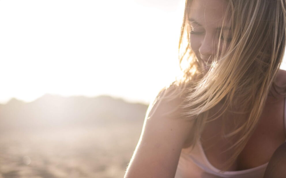 Glückliche Frau in der Landschaft mit verwehtem Haar