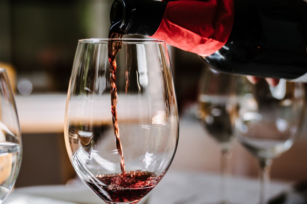 Einfüllen einer Flasche Rotwein in ein schönes Weinglas im Restaurant im Hotel Lech