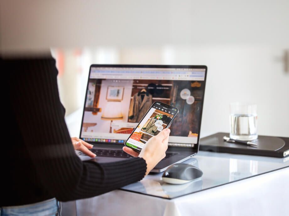 Mitarbeiterin, die auf ihrem Laptop und ihrem Smartphone eine Kundenwebsite überprüft