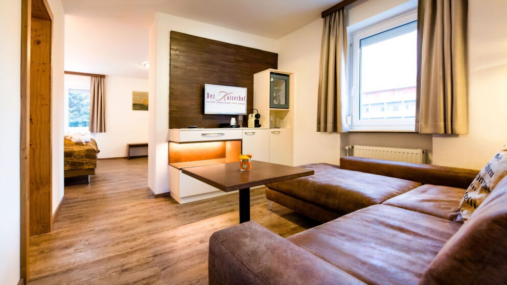 Suite mit Wohnzimmer und großer braunen Wohnlandschaft mit Fernseher im Kaiserhof