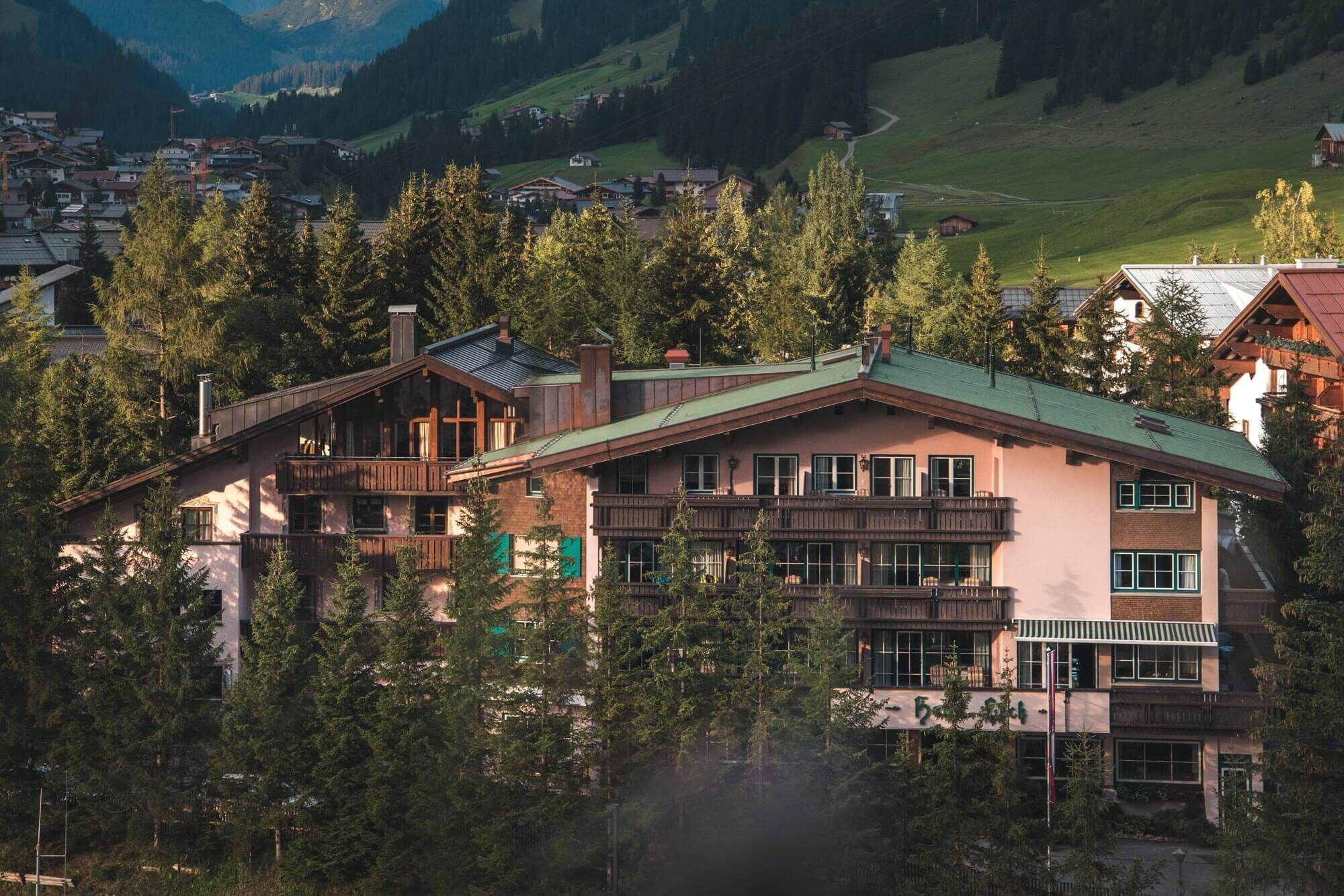 Hotel Lech inmitten eines kleinen Nadelbaumwaldes in Vorarlberg