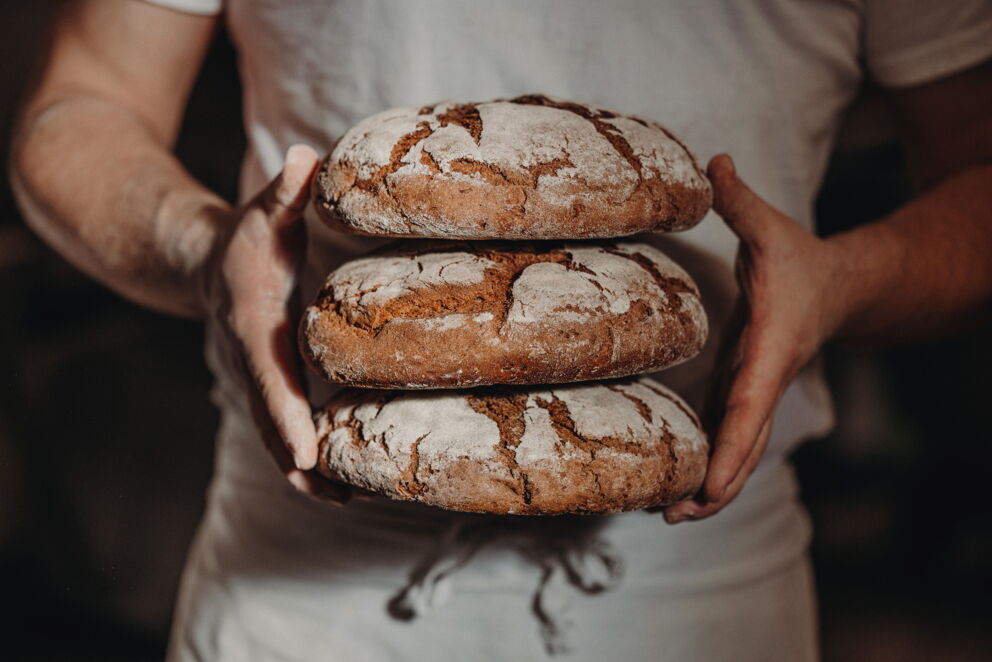 Bäcker mit frischen 3 Laib gebackenes Schwarzbrot