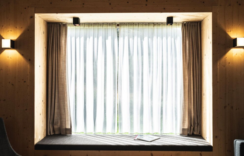 Großes Panoramafenster mit Liegemöglichkeit in den Trattler Hof-Chalets in Kärnten