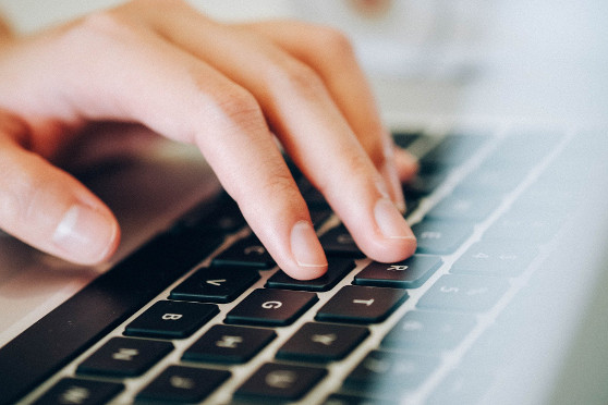 Die Hand einer Frau liegt auf einer Macbook Tastatur